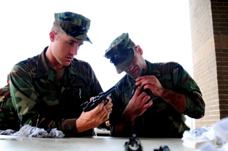 US Navy 081017-N-0411D-020 Lt. Timm Heisey, left, and Electronics Technician 1st Class Justin Donette clean their Beretta 9mm pistols at the armory's cleaning station. Heisey and Donnette are training in handgun marksmanship photo