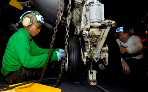 US Navy 081020-N-4954I-003 Aviation Structural Mechanic 3rd Class Amber Scott and Aviation Structural Mechanic 3rd Class Mike Vaneerde tighten screws on the landing gear of an E-2C Hawkeye