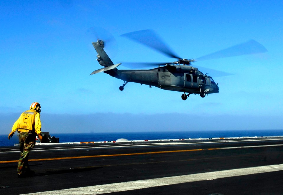 US Navy 081021-N-9928E-025 Aviation Boatswain's Mate (Handling) 2nd Class Daniel Lynn from Modesto, Calif., leans into the rotor wash of an MH-60S Sea Hawk helicopter assigned to the