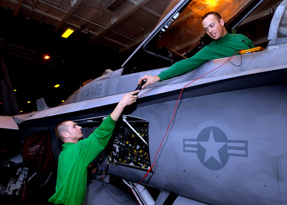 US Navy 081020-N-4954I-005 Aviation Electronics Technician 3rd Class Ryan Clogston hands a flashlight to Aviation Electronics Technician 3rd Class Jacob Riese