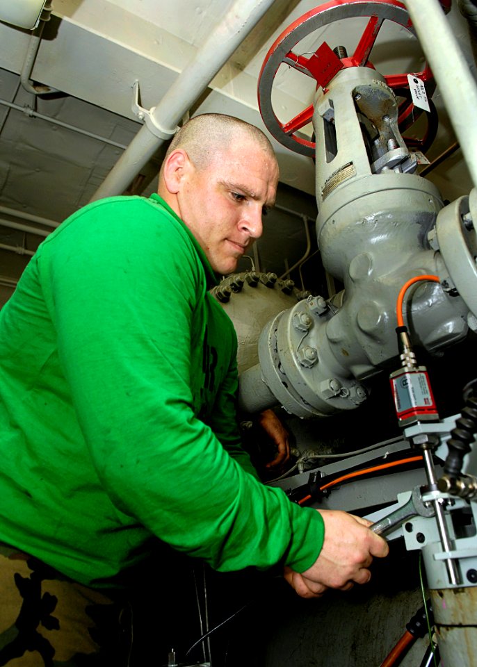 US Navy 081022-N-4954I-006 Aviation Boatswain's Mate (Equipment) 3rd Class Andy Boucher performs maintenance on an aircraft catapult hydraulic system