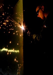 US Navy 081023-N-9900B-005 Hull Maintenance Technician 3rd Class Jon Frydenlund welds together a tool cage