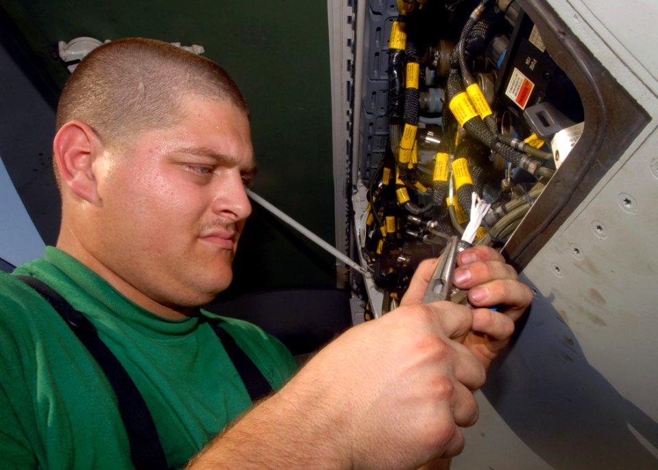 US Navy 081024-N-2456S-143 Aviation Electronics Technician 3rd Class Jason Franks repairs a wire on an electrical unit