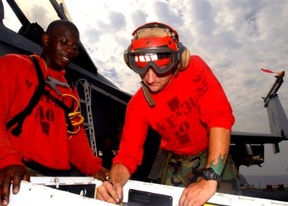 US Navy 081022-N-2456S-020 Aviation Ordnanceman 1st Class Charles Richardson shows Aviation Ordnanceman Airman Curtis Johnson how to prepare the rounds for the 20mm Vulcan gun