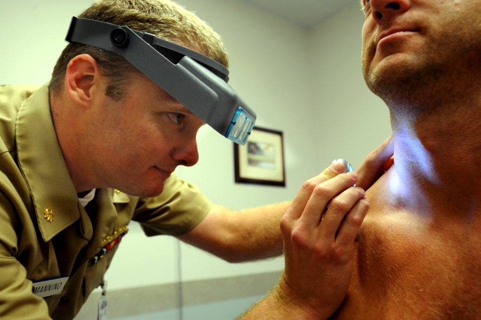 US Navy 081023-N-2959L-063 Lt. Cmdr. Stephen Mannino examines a Sailor using a dermatascope and magnifying loops photo