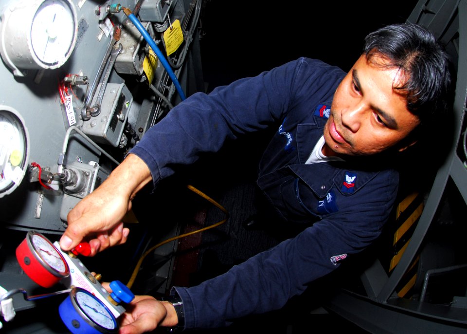 US Navy 081024-N-5148B-010 Machinist's Mate 2nd Class Rodel Alfonso checks pressure on a refrigeration unit aboard the amphibious assault ship USS Peleliu (LHA 5). Peleliu is the flagship of the Peleliu Expeditionary Strike Gro