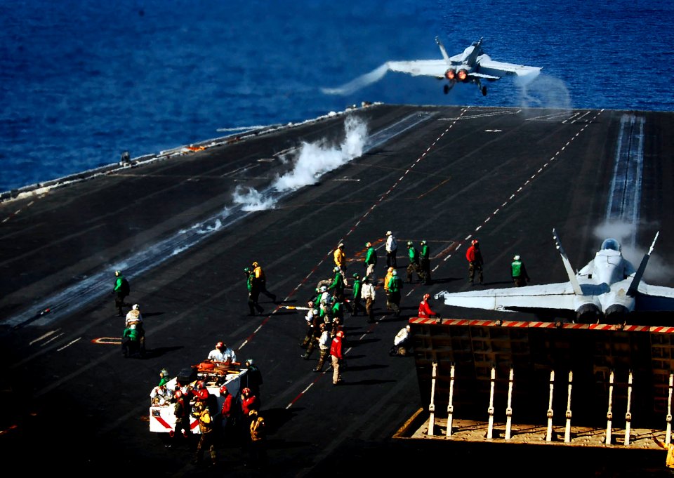 US Navy 081101-N-6538W-315 n F-A-18E Super Hornet launches while an F-A-18C repares to launch from the flight deck of the Nimitz-class aircraft carrier USS John C. Stennis (CVN 74)