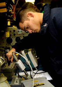 US Navy 081026-N-4954I-006 Aviation Electronics Technician 3rd Class Lawrence Imamura conducts relay checks on a control box