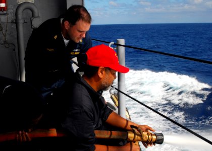 US Navy 081030-N-5148B-064 Chief Hull Technican Heath Hardy watches as David Ward discharges a fire hose