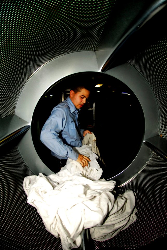 US Navy 081103-N-6538W-032 hip's Serviceman Seaman Apprentice Kyle Estrella removes bed sheet linens from a dryer