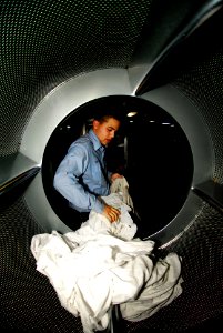 US Navy 081103-N-6538W-032 hip's Serviceman Seaman Apprentice Kyle Estrella removes bed sheet linens from a dryer
