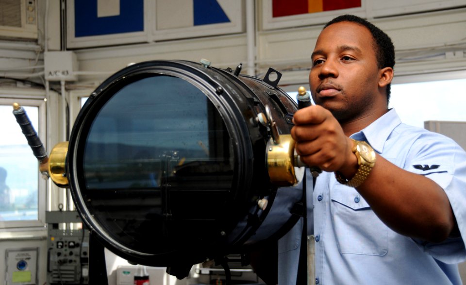 US Navy 081104-N-9758L-009 Quartermaster 3rd Class Karlo Broussard communicates with ships in Pearl Harbor using a signal lamp in the Naval Station Pearl Harbor Signal Control Tower