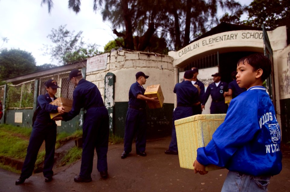 US Navy 081028-N-5253W-006 A young Filipino student looks on as Sailors unload boxes of supplies