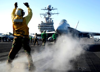 US Navy 081103-N-7571S-009 An Aviation Boatswain's Mate (Handling) directs an F-A-18 Hornet to a catapult during flight operations aboard the aircraft carrier USS Theodore Roosevelt (CVN 71)