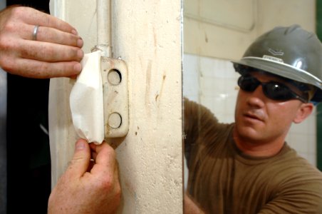 US Navy 081030-N-7544A-078 Builder 2nd Class Sean Roberts Sr. tapes an electrical outlet in preparation for painting photo