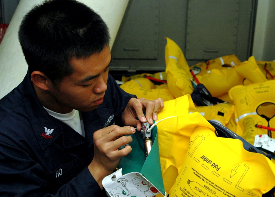US Navy 090127-N-9134V-010 Boatswain's Mate 2nd Class Chinh Ho conducts preventive maintenance on a Stearns life preserver