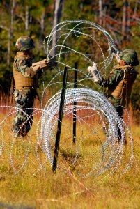 US Navy 081104-N-7367K-009 Gunner's Mate 2nd Class Amanda Hung, left, and Gunner's Mate 2nd Class Ava Dean, both assigned to Naval Mobile Construction Battalion (NMCB) 1, set up concertina wire around the ammunition supply poin