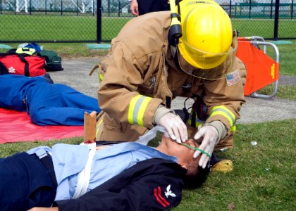 US Navy 081106-N-0483B-002 A firefighter assigned to the Commander, U.S. Naval Forces Japan (CNFJ) regional fire department places an oxygen mask on a simulated victim during a joint mass casualty exercise at Fleet Activities photo