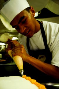 US Navy 090223-N-2475A-041 Culinary Specialist 3rd Class Alexander Boone places icing on the edge of a cake photo