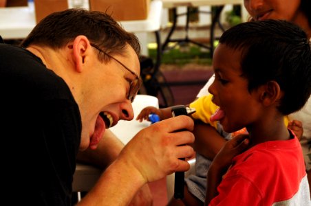 US Navy 081105-N-8907D-044 Lt. Cmdr. Kenn Norris, currently embarked aboard the amphibious assault ship USS Kearsarge (LHD 3), checks the throat of a little boy at the Couva District Health Facility during the humanitarian-civi photo