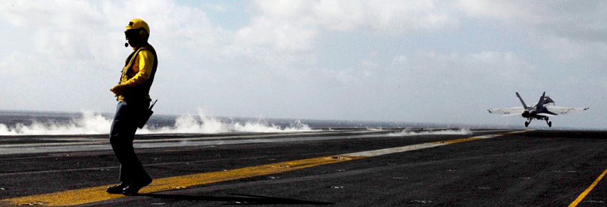 US Navy 081109-N-6538W-049 Aviation Boatswain's Mate (Handling) 3rd Class Kyle Cowell, from Sylvania, Ohio, braces against wind and jet exhaust as an F-A-18E Super Hornet launches from the aircraft carrier USS John C. Stennis