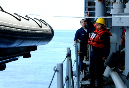 US Navy 091016-N-7478G-235 Boatswain's Mate 2nd Class Ee Vue directs the line handlers to heave a rigid-hull inflatable boat (RHIB)