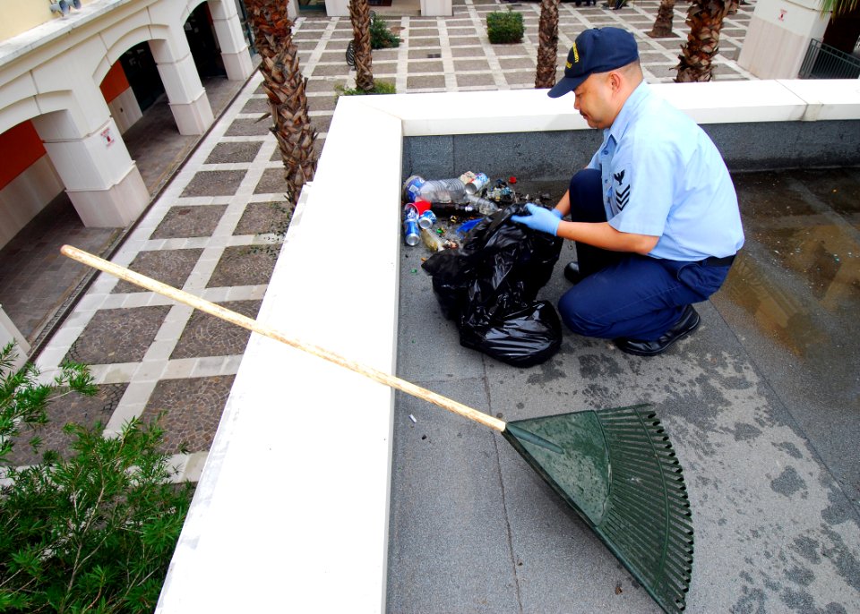 US Navy 081107-N-4044H-015 ulinary Specialist 1st Class Gualberto Magdaluyo scoops trash in a pile for pickup during bachelor housing's first