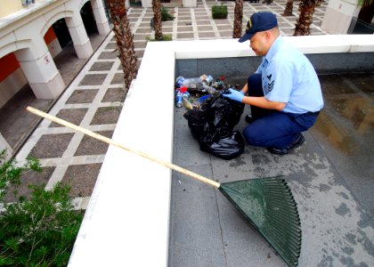 US Navy 081107-N-4044H-015 ulinary Specialist 1st Class Gualberto Magdaluyo scoops trash in a pile for pickup during bachelor housing's first