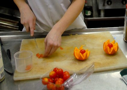 US Navy 081107-N-9132C-042 Culinary Specialist Seaman Jessica Menz, from Minn., carves an orange and cherry tomatoes into a fruit sculpture in the Chief Petty Officer's Mess aboard the Nimitz-class aircraft carrier USS Ronald R