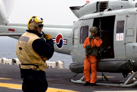 US Navy 081107-N-9950J-017 Aviation Boatswain's Mate (Handling) 3rd Class Apolinar Garcia, from San Diego, communicates with flight-deck control before launching a Republic of Korea (ROK) UH-1 Huey helicopter