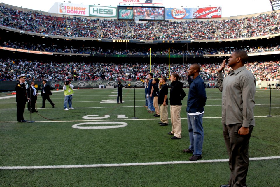 US Navy 081109-N-9818V-621 Rear Adm. Terence E. McKnight reads the oath of enlistment for a group of future service members during half time at the Meadowlands