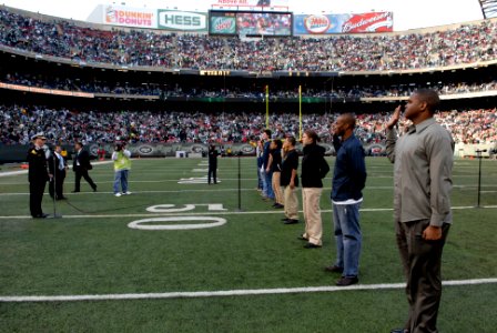 US Navy 081109-N-9818V-621 Rear Adm. Terence E. McKnight reads the oath of enlistment for a group of future service members during half time at the Meadowlands photo