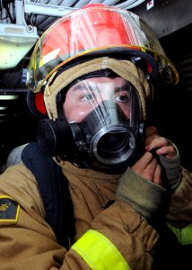 US Navy 081113-N-9758L-034 A Sailor assigned to the Pearl Harbor-based Arleigh Burke-class guided-missile destroyer USS Paul Hamilton (DDG 60) dons a fire-fighting helmet during a fire drill in the ship's personnel office