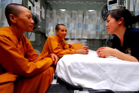 US Navy 100607-N-4044H-002 Iris Vuong speaks with Buddhist monks as they wait to be seen by a doctor