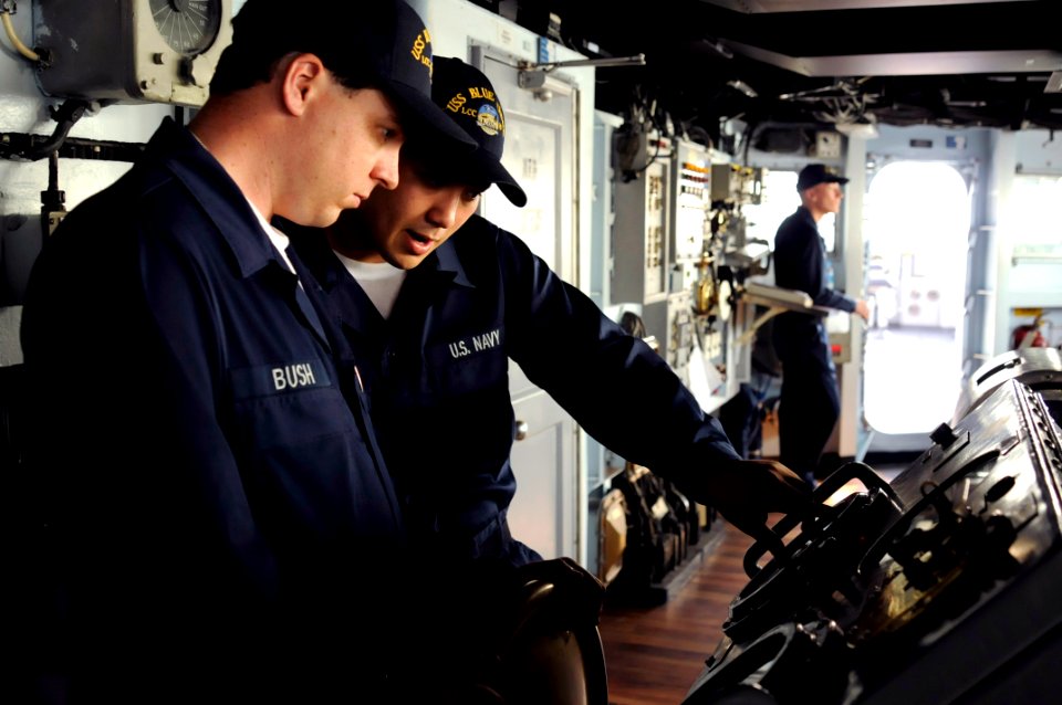 US Navy 081117-N-8546L-024 Deck Seaman William Joseph Bush, left, from Kranzburg, S.D., takes the helm for the first time of the amphibious command ship USS Blue Ridge (LCC 19) under instruction from Seaman Walter Frank, from C