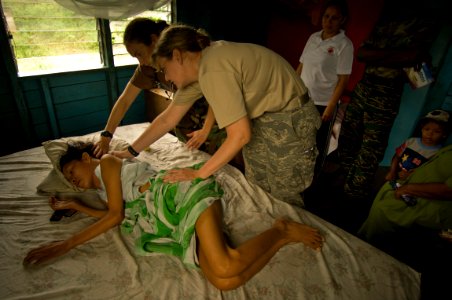 US Navy 081116-N-9620B-004 Capt. Amber Tyler and Lt. Amanda McCaulley, both embarked aboard the amphibious assault ship USS Kearsarge (LHD 3), give a medical examination to a local woman photo
