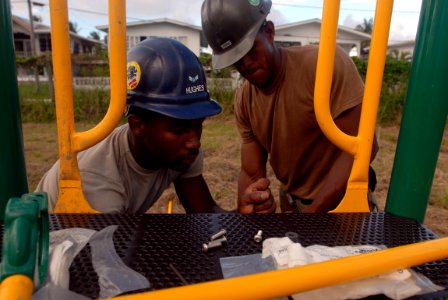US Navy 081117-N-3595W-092 Air Force Airman 1st Class Pasha Hughes and Engineering Aide 2nd Class Hugo Lerma work together building a new playground for a local community