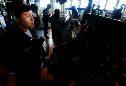 US Navy 100720-N-7948R-058 Boatswain's Mate Seaman Bethany Paquet mans the helm in the bridge aboard USS Pearl Harbor (LSD 52)
