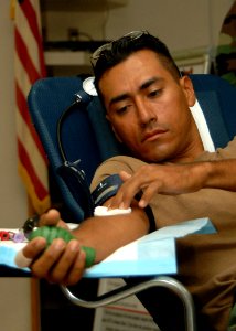 US Navy 081122-N-8816D-113 Engineering Aide Constructionman Roberto Diaz, assigned to Naval Mobile Construction Battalion (NMCB) 133, applies pressure to a gauze on his arm after donating blood during a blood drive hosted by NM