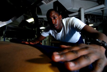 US Navy 081120-N-9950J-055 Mass Communication Specialist Seaman Apprentice Taurean Alexander, from Fresno, Calif., creases a pair of coveralls while working as a laundry service assistant in the laundry room of the forward-depl
