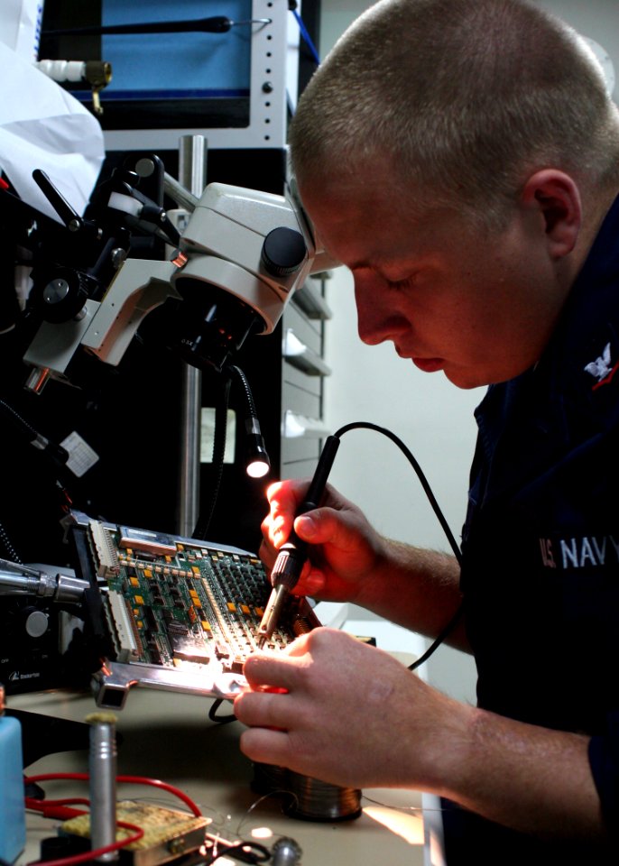 US Navy 081202-N-6764G-093 Electronics Technician 3rd Class Scott Clark repairs a circuit board