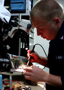 US Navy 081202-N-6764G-093 Electronics Technician 3rd Class Scott Clark repairs a circuit board