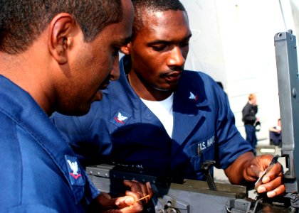 US Navy 081127-N-6764G-014 Personnel Specialist 3rd Class Timothy Sidial and Fire Controlman 3rd Class Rodregous Johnson perform maintenance on a .50 caliber machine gun