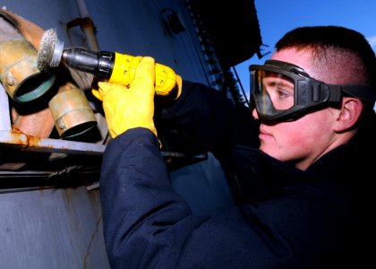 US Navy 081201-N-9898L-068 viation Boatswain's Mate Airman Mitchell Larson removes corrosion from a fire hose