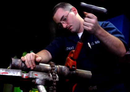 US Navy 081203-N-8822R-023 Hull Maintenance Technician Fireman Apprentice Josh Lonas uses a pipe cutter to cut a pipe