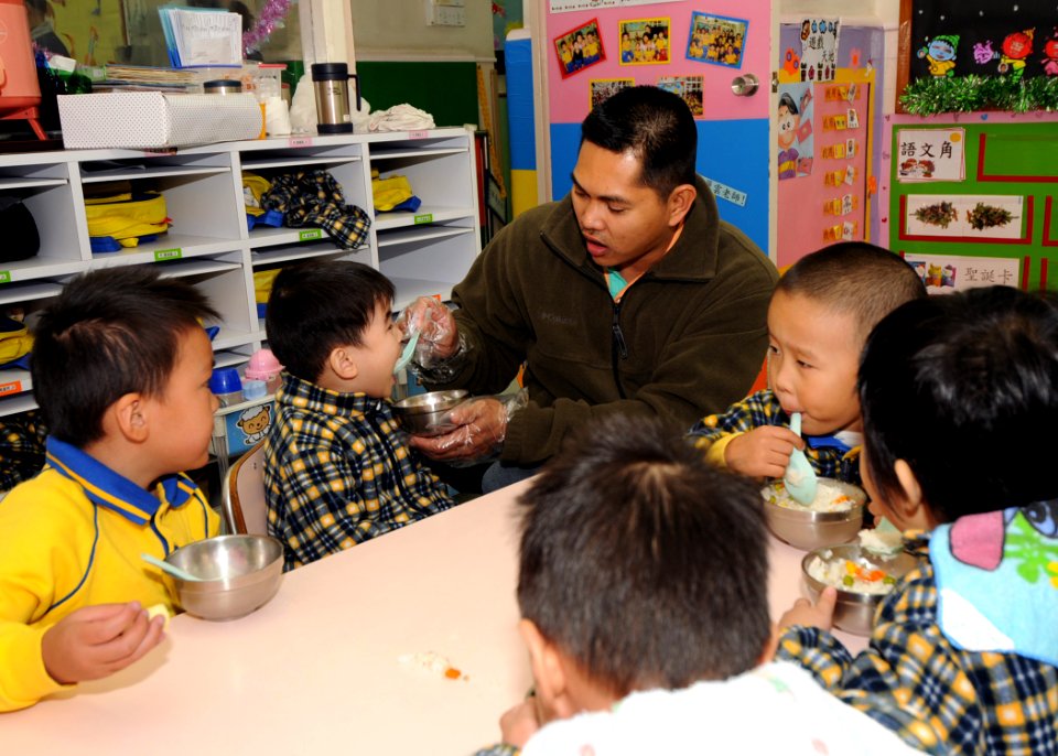 US Navy 081128-N-3262C-124 Chief Fire Controlman Eduardo M. Pareno helps feed a student from the Hong Kong Society for the Protection of Children during a community relations project. The Society serves as a nursery school for
