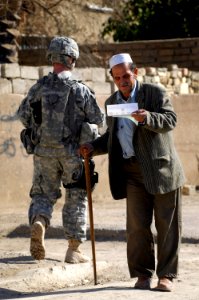 US Navy 081206-N-1810F-102 An Iraqi man pauses to read over a leaflet given to him by a Iraqi National Policeman during a joint U.S. Army Iraqi police walking patrol through the Rashid community in Bahgdad photo