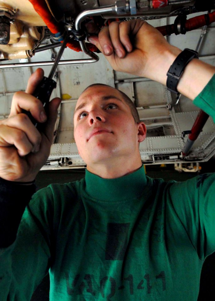 US Navy 081129-N-2456S-055 Aviation Electrician's Mate 3rd Class Lonnie Pope, assigned to VAQ-141, installs a clamp on the starter generator lines of an EA-6B Prowler in the hangar bay aboard the aircraft carrier USS Theodore R