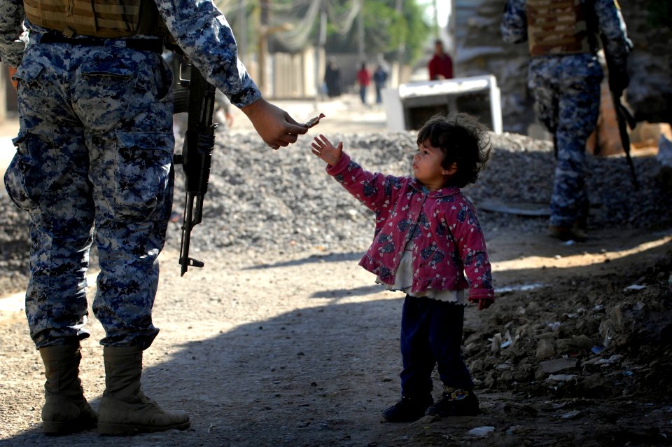 US Navy 081206-N-1810F-137 An Iraqi National Policeman gives candy to a child while on a walking patrol through the Rashid community in Bahgdad