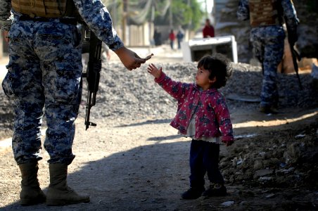 US Navy 081206-N-1810F-137 An Iraqi National Policeman gives candy to a child while on a walking patrol through the Rashid community in Bahgdad photo